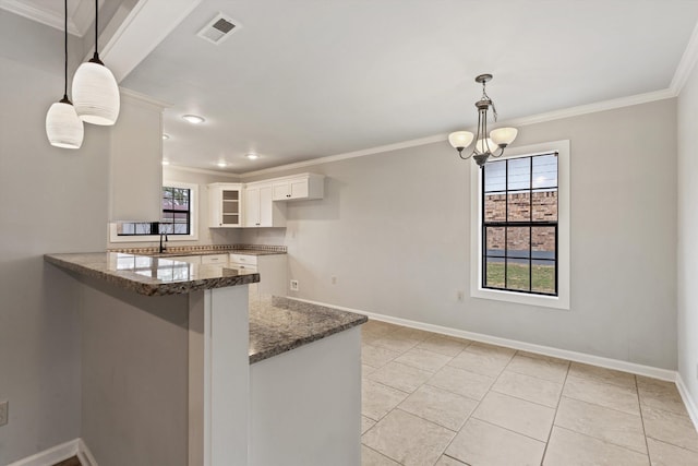 kitchen with dark stone countertops, hanging light fixtures, kitchen peninsula, and white cabinets