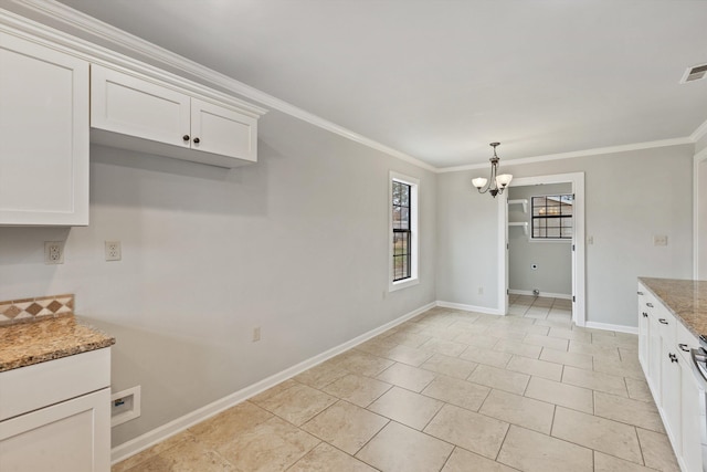 kitchen with stone counters, ornamental molding, an inviting chandelier, and white cabinets