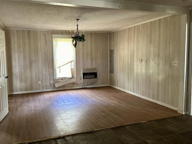 unfurnished living room featuring heating unit, dark hardwood / wood-style flooring, ornamental molding, a notable chandelier, and electric panel