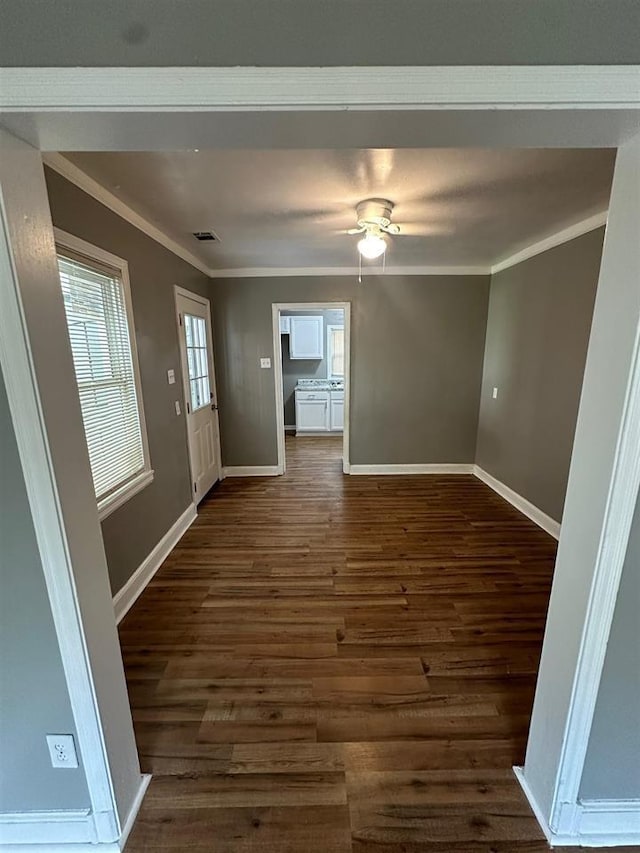 interior space with dark wood-type flooring, ornamental molding, and ceiling fan