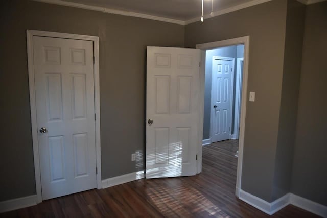 unfurnished bedroom featuring crown molding and dark wood-type flooring