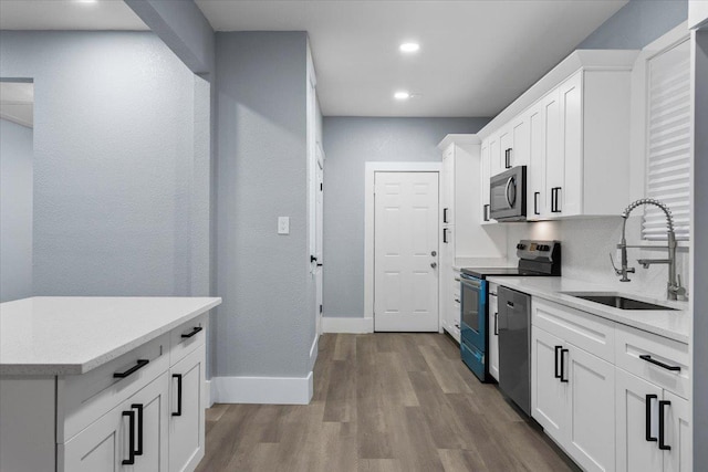 kitchen with white cabinetry, sink, wood-type flooring, and stainless steel appliances