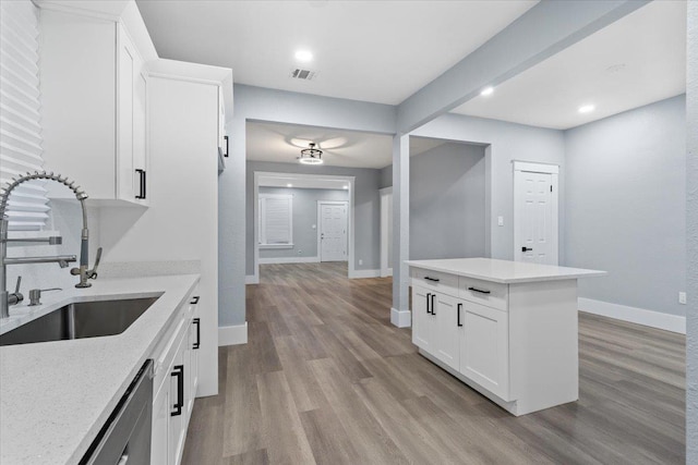 kitchen featuring white cabinetry, light stone countertops, sink, and light hardwood / wood-style flooring