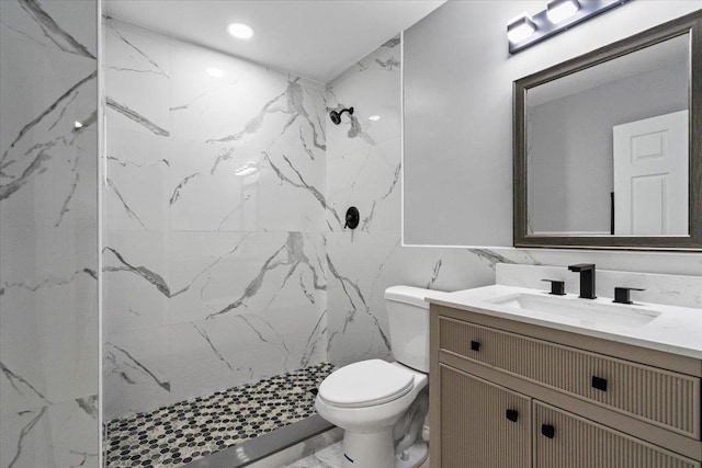 bathroom featuring vanity, toilet, and a tile shower