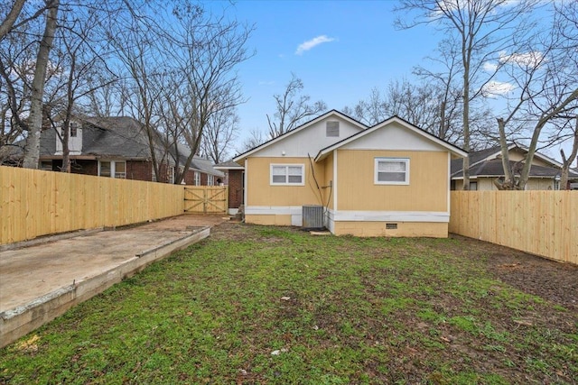 rear view of house with cooling unit and a lawn