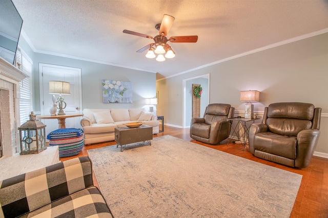 living room with ornamental molding, a brick fireplace, hardwood / wood-style floors, and a textured ceiling