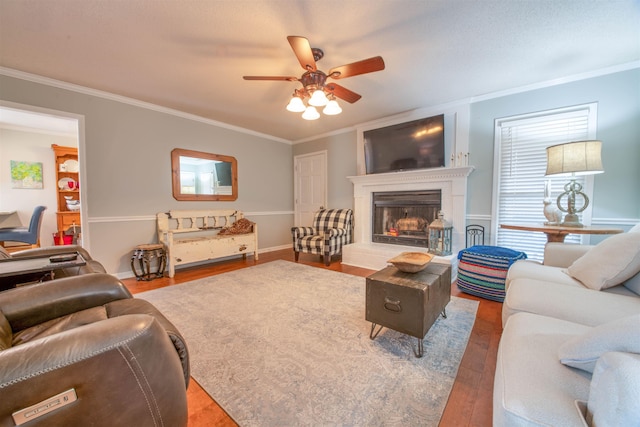 living room with ornamental molding, wood-type flooring, and ceiling fan