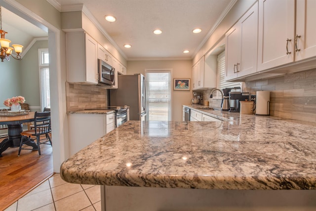 kitchen with sink, white cabinetry, ornamental molding, appliances with stainless steel finishes, and kitchen peninsula