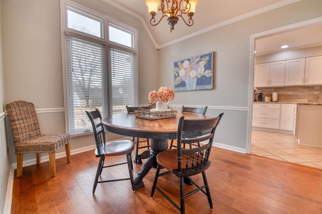 dining space with an inviting chandelier, crown molding, and light wood-type flooring