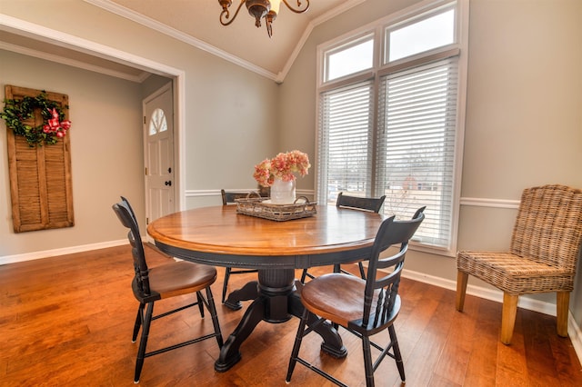 dining space with an inviting chandelier, wood-type flooring, ornamental molding, and vaulted ceiling