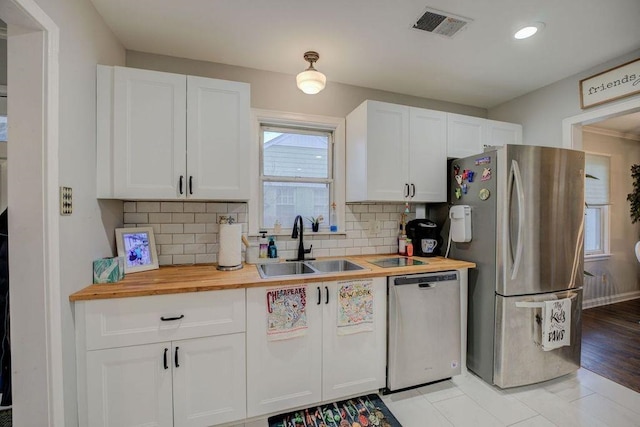 kitchen featuring white cabinetry, sink, wooden counters, backsplash, and stainless steel appliances