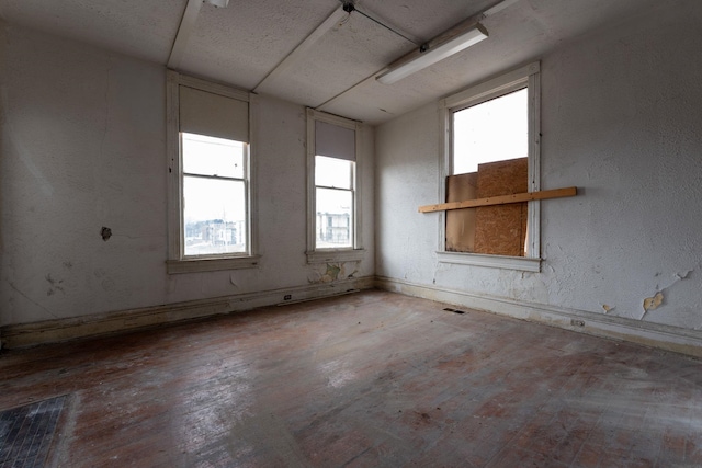 empty room with a wealth of natural light and wood-type flooring