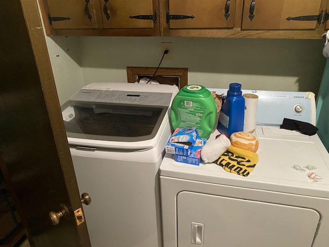 clothes washing area featuring cabinets and washing machine and clothes dryer