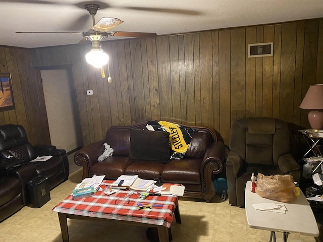 living room featuring ceiling fan and wooden walls