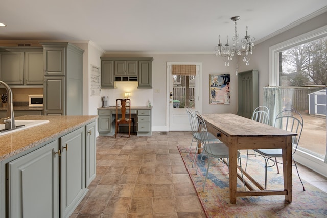 dining room featuring sink, built in desk, ornamental molding, and a chandelier