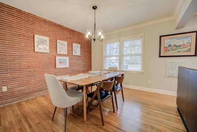 dining room with crown molding, brick wall, an inviting chandelier, and light hardwood / wood-style flooring