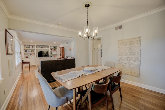 dining room with crown molding, built in shelves, light hardwood / wood-style floors, and a notable chandelier