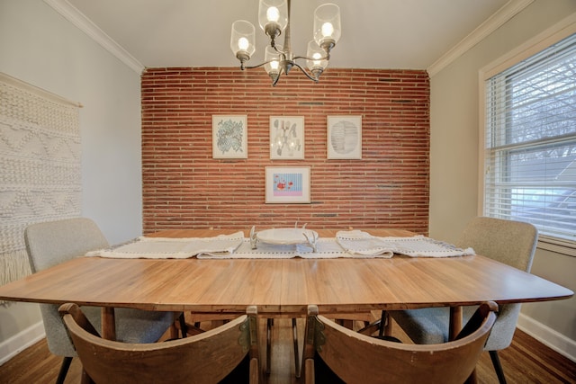 dining room with dark wood-type flooring, brick wall, ornamental molding, and a notable chandelier