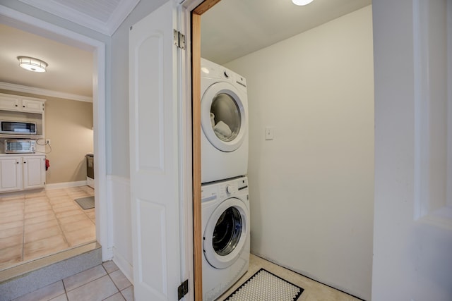 laundry room featuring crown molding, stacked washer / dryer, and light tile patterned floors