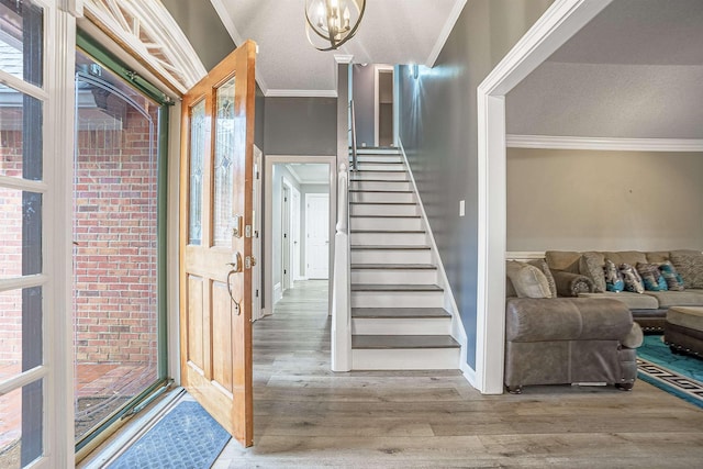 staircase with a textured ceiling, wood-type flooring, ornamental molding, and a chandelier