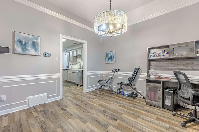 office space with sink, a notable chandelier, ornamental molding, and light wood-type flooring