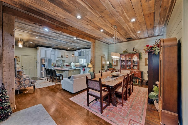 dining room with dark wood-type flooring, wooden ceiling, and wooden walls