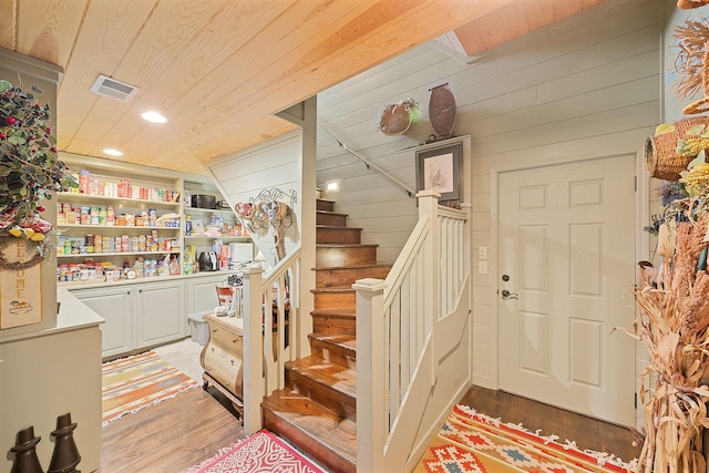 stairway featuring wood-type flooring, wooden ceiling, and wooden walls