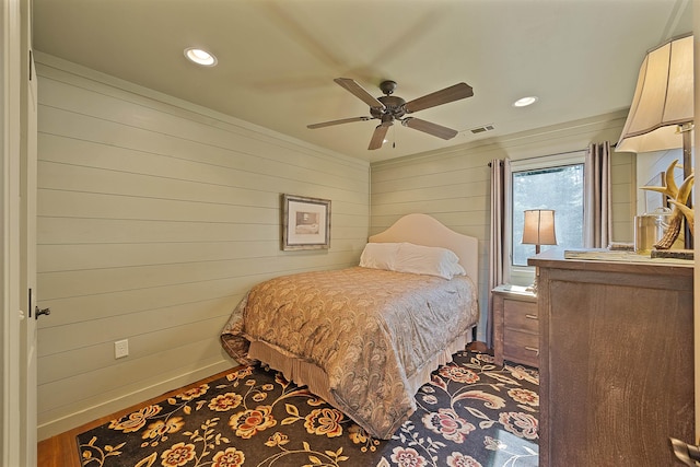 bedroom featuring hardwood / wood-style floors, ceiling fan, and wood walls