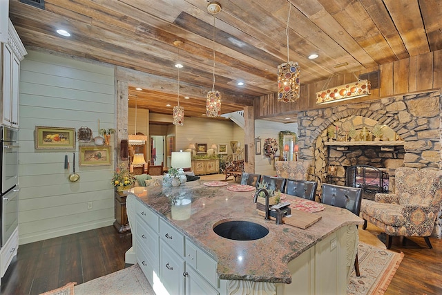 kitchen with a center island with sink, white cabinets, and decorative light fixtures