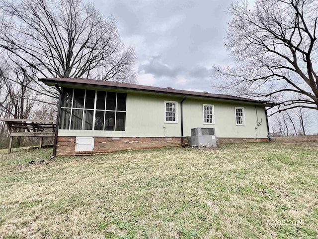 back of property with central AC unit, a yard, and a sunroom