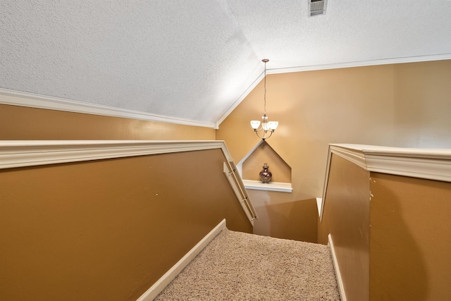 stairway featuring vaulted ceiling, ornamental molding, and a textured ceiling