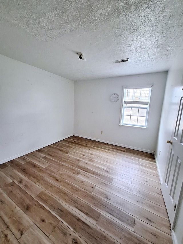 empty room featuring a textured ceiling and light wood-type flooring