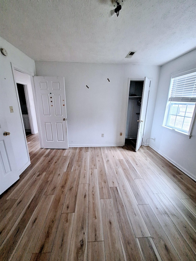 unfurnished bedroom featuring a textured ceiling and light hardwood / wood-style flooring