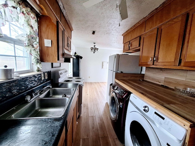 kitchen with hardwood / wood-style floors, white range with electric stovetop, separate washer and dryer, sink, and a textured ceiling