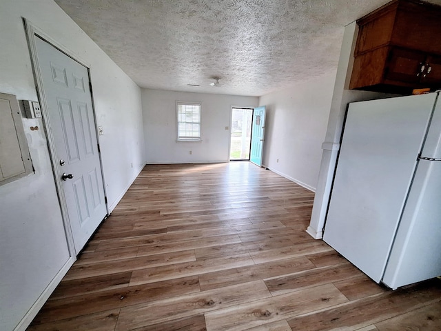 interior space with light hardwood / wood-style flooring, a textured ceiling, and white refrigerator