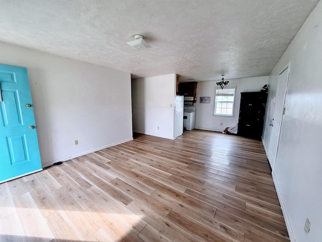 unfurnished living room with a notable chandelier, a textured ceiling, and light wood-type flooring