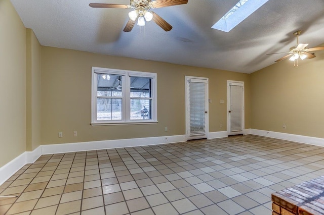 spare room featuring lofted ceiling with skylight, light tile patterned floors, ceiling fan, and a textured ceiling