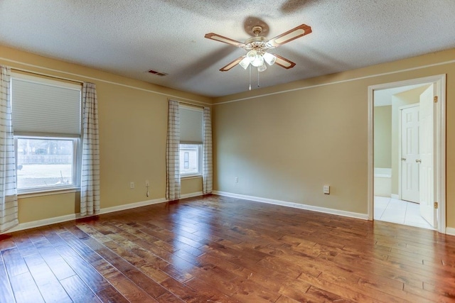 empty room with ceiling fan, hardwood / wood-style floors, and a textured ceiling