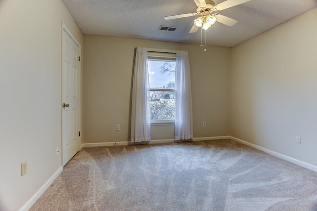 spare room featuring ceiling fan, light colored carpet, and a textured ceiling