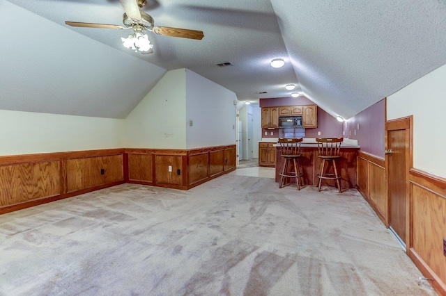 additional living space featuring ceiling fan, light colored carpet, vaulted ceiling, and a textured ceiling