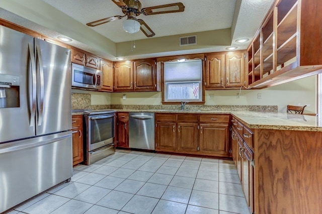 kitchen with appliances with stainless steel finishes, sink, light tile patterned floors, ceiling fan, and a textured ceiling