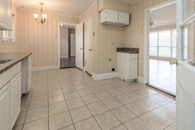 kitchen with white cabinetry, crown molding, hanging light fixtures, and light tile patterned floors