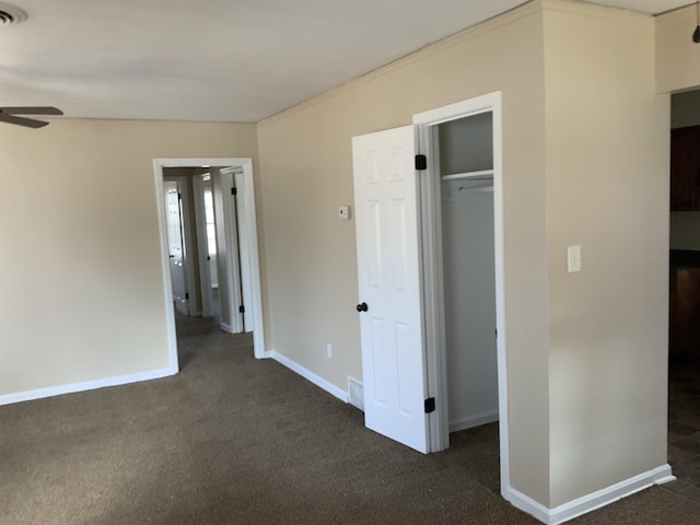 unfurnished bedroom featuring a spacious closet, a closet, and dark colored carpet