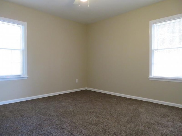 unfurnished room with a healthy amount of sunlight and dark carpet