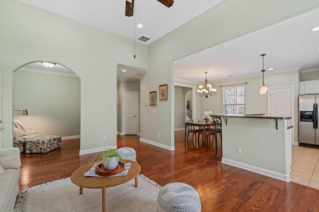 living room featuring ornamental molding, wood-type flooring, and ceiling fan with notable chandelier