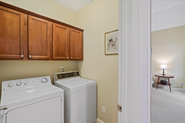 laundry room featuring light colored carpet, cabinets, and washing machine and clothes dryer