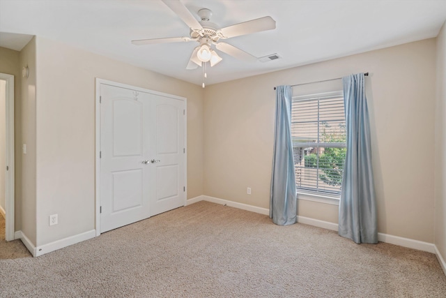 unfurnished bedroom featuring light carpet, ceiling fan, and a closet