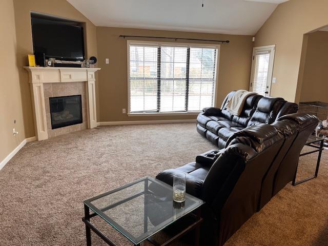 carpeted living room featuring a tiled fireplace and vaulted ceiling