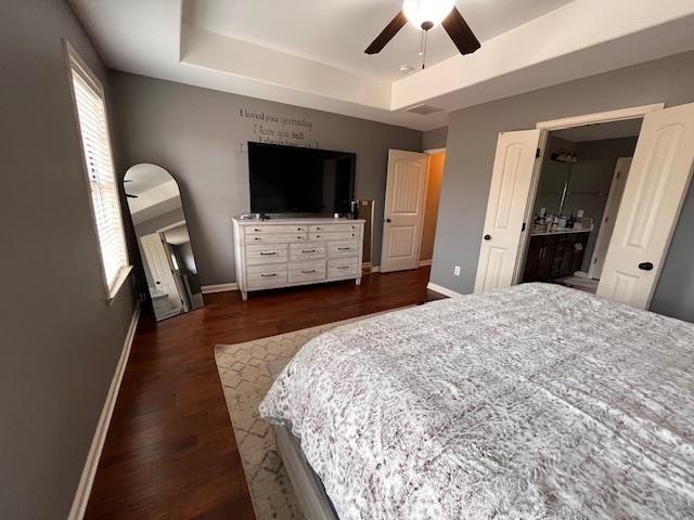 bedroom featuring a tray ceiling, dark wood-type flooring, and ceiling fan