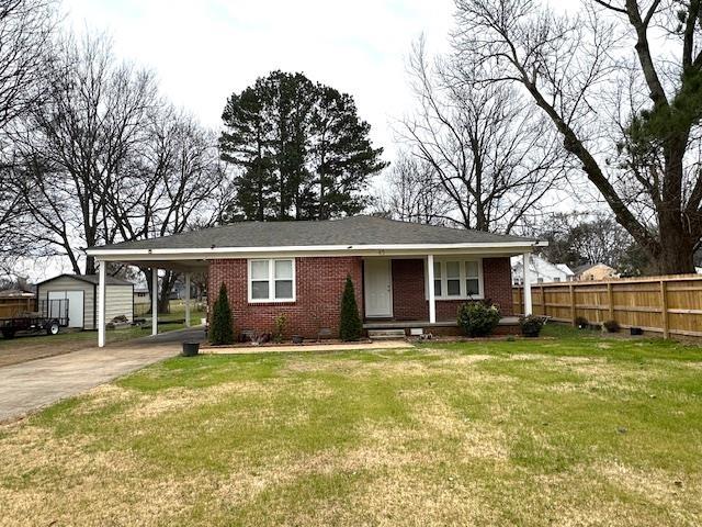 view of front facade with a carport, a front lawn, and a storage unit